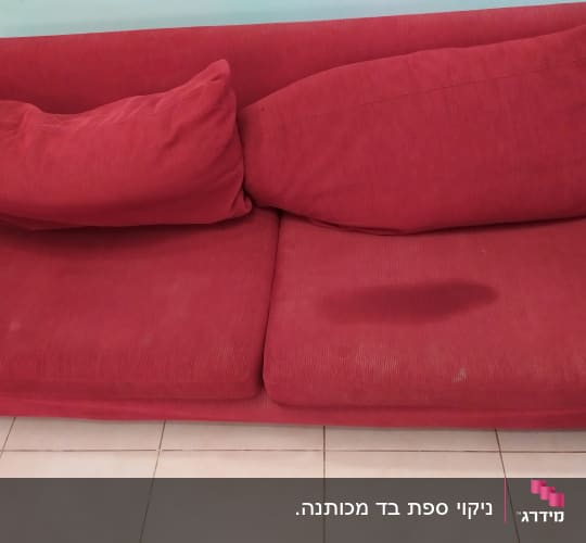 ספה אדומה עם כתם כהה על המושב